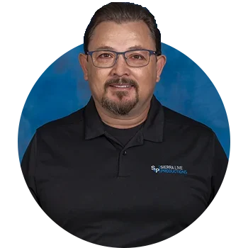 A man in glasses and black shirt standing next to blue background.